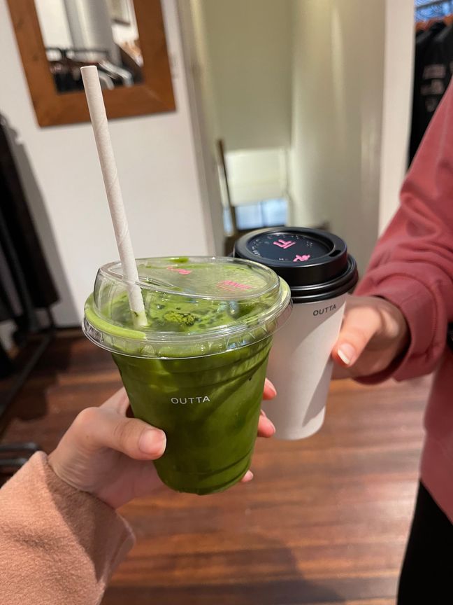 Cup of iced matcha and latte held next to each other