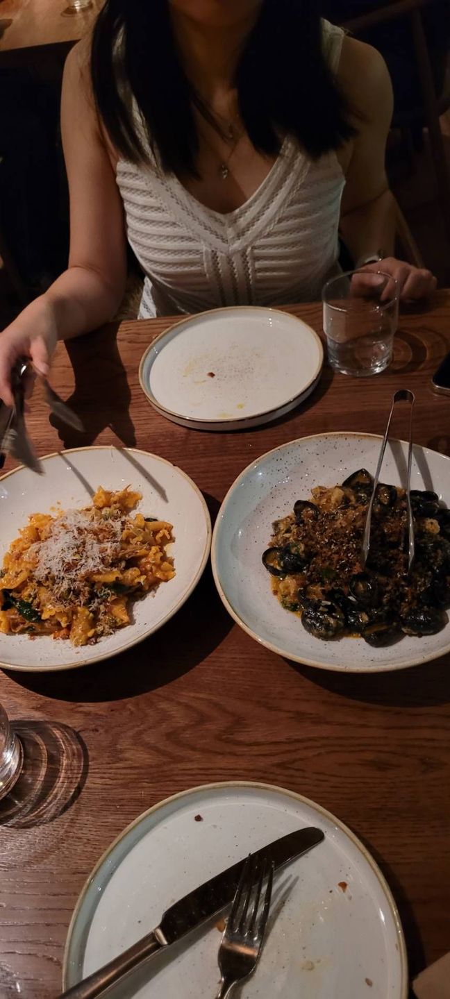 Photo of two pasta dishes, where one is a squid ink and mussel pasta and the other is a duck ragu dish.
