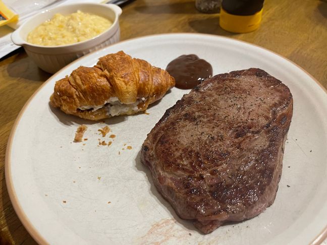 Photo of steak, croissant with cream cheese, and corn soup