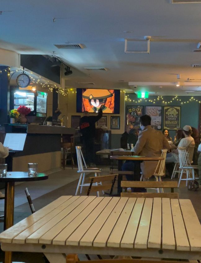 Photo of the inside of Chippo Hotel pub, showing a screen with Avatar the Last Airbender playing.