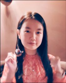 Portrait of Wing Pang smiling wearing a pink dress while holding a spoon.